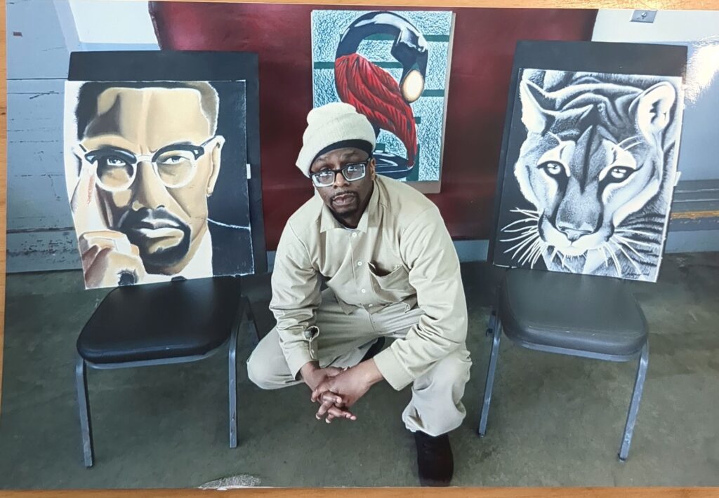 A picture of Lawrence in front of three paintings that he created.
