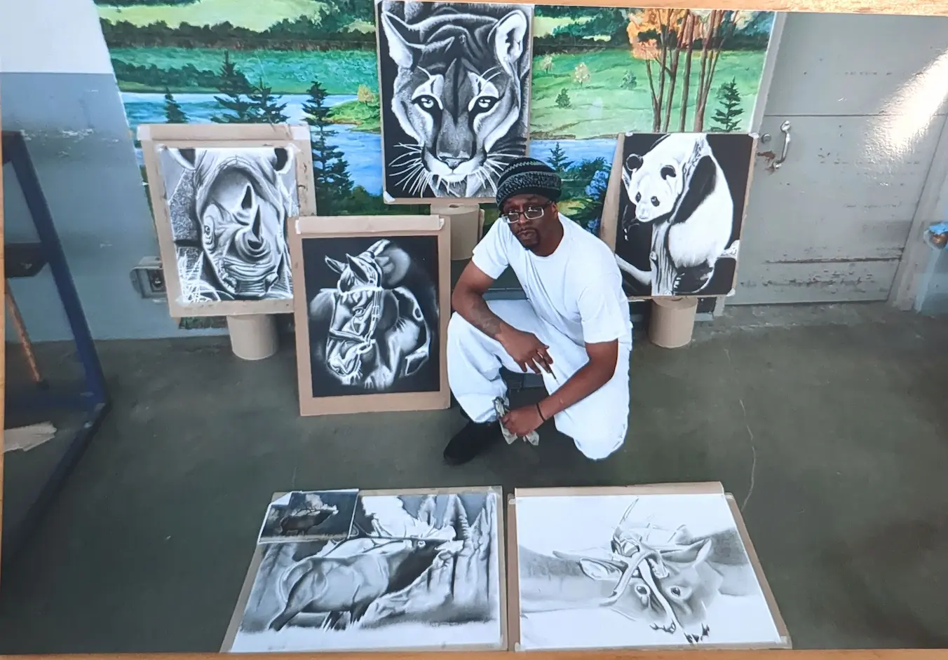 A photo of L crouched in front of a display of his animal series.