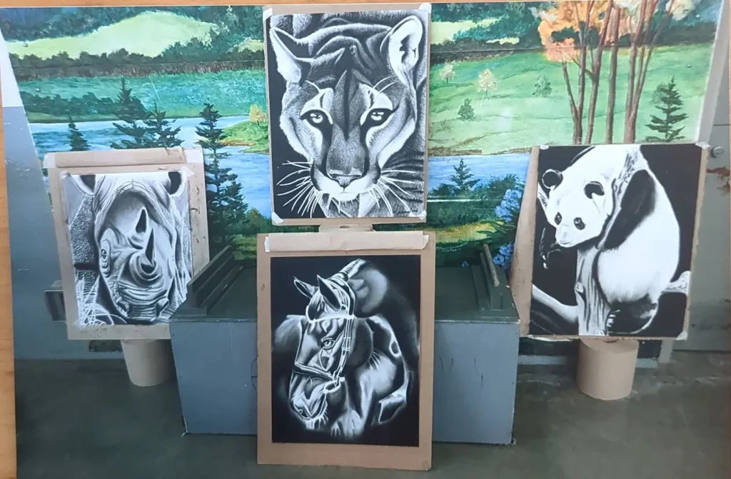 A photo of four black and white pieces done by Lawrence Jenkins. One piece features a rhino. The second piece features a panther. The third piece features a horse. The last piece is a panda.)